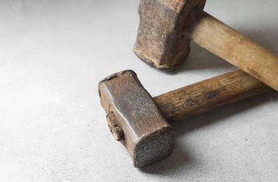 Two sledgehammers on grey background, closeup. Space for text