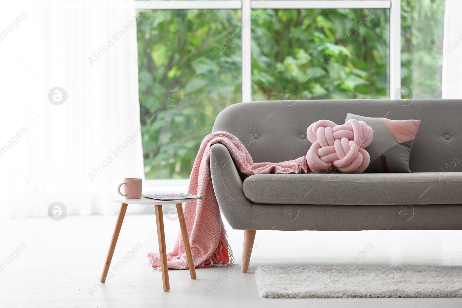 Photo of Pillows and plaid on sofa in living room interior. Unusual cushion design