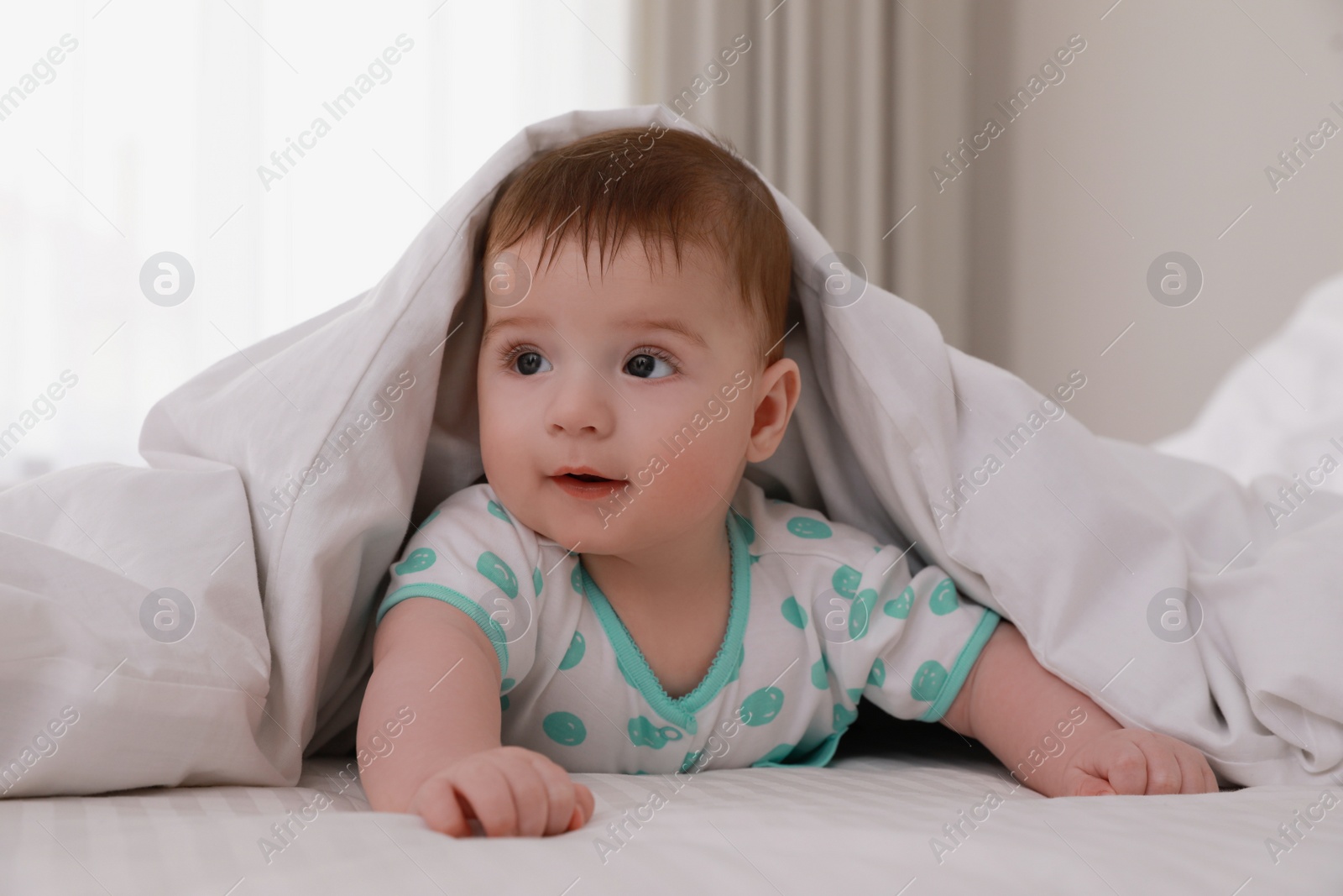 Photo of Cute little baby in bed under soft blanket indoors