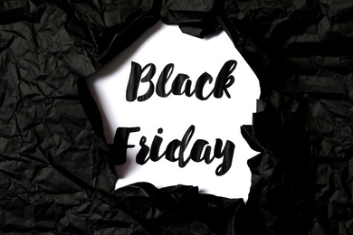 Photo of Phrase Black Friday on white background, view through hole in torn paper