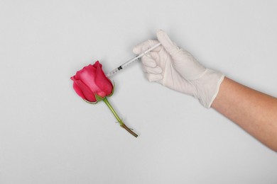 Photo of Doctor making injection to rose on light grey background, top view