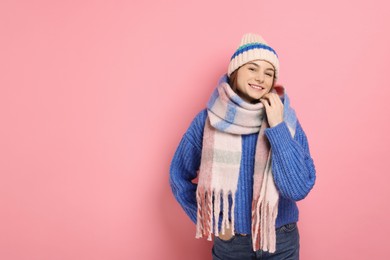 Photo of Beautiful woman in warm scarf and hat on pink background, space for text