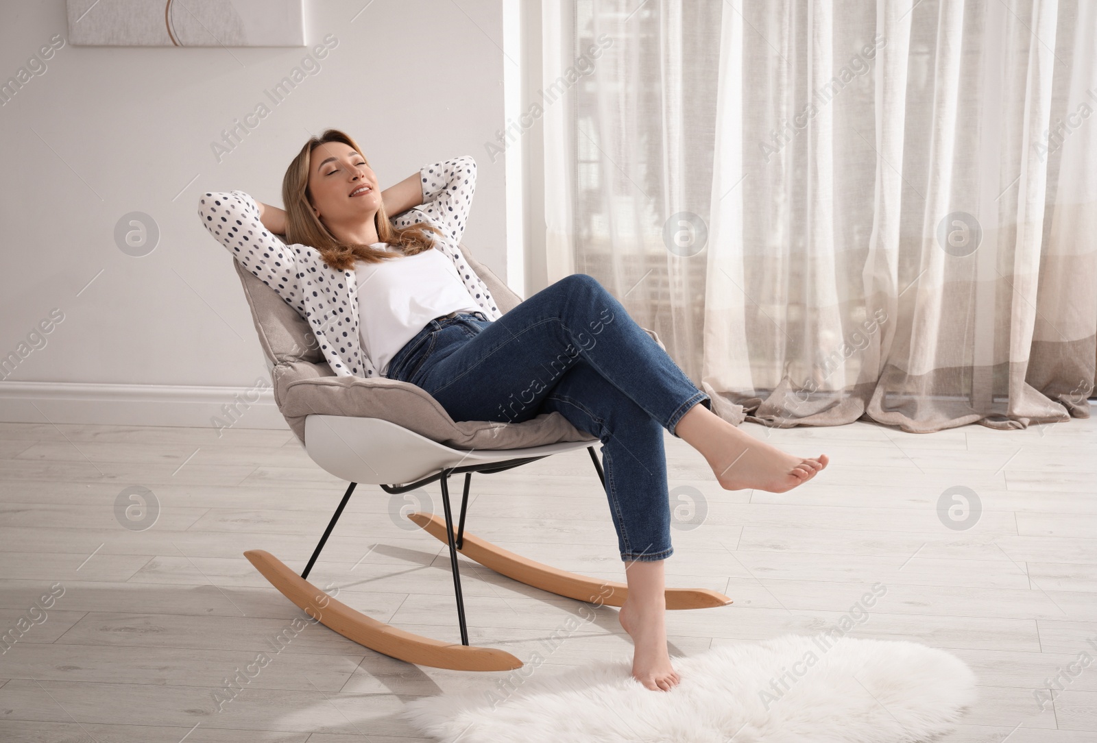 Photo of Beautiful young woman sitting in rocking chair at home