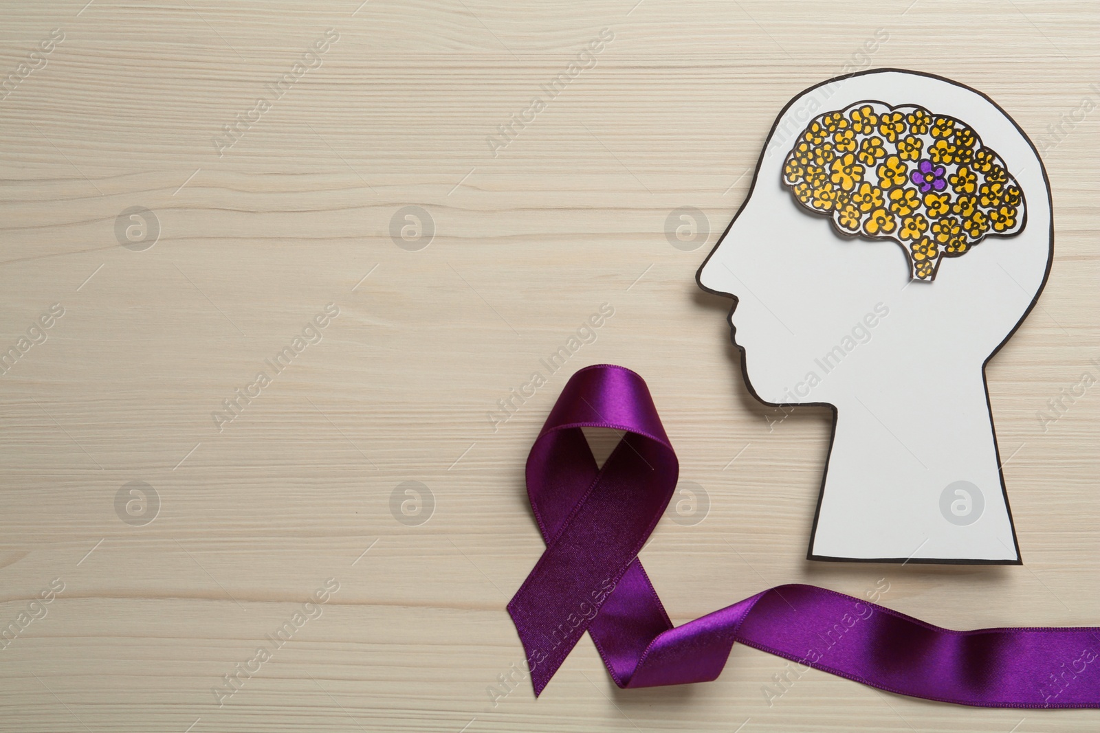 Photo of Top view of human head cutout with brain and purple ribbon on white wooden background, space for text. Epilepsy awareness