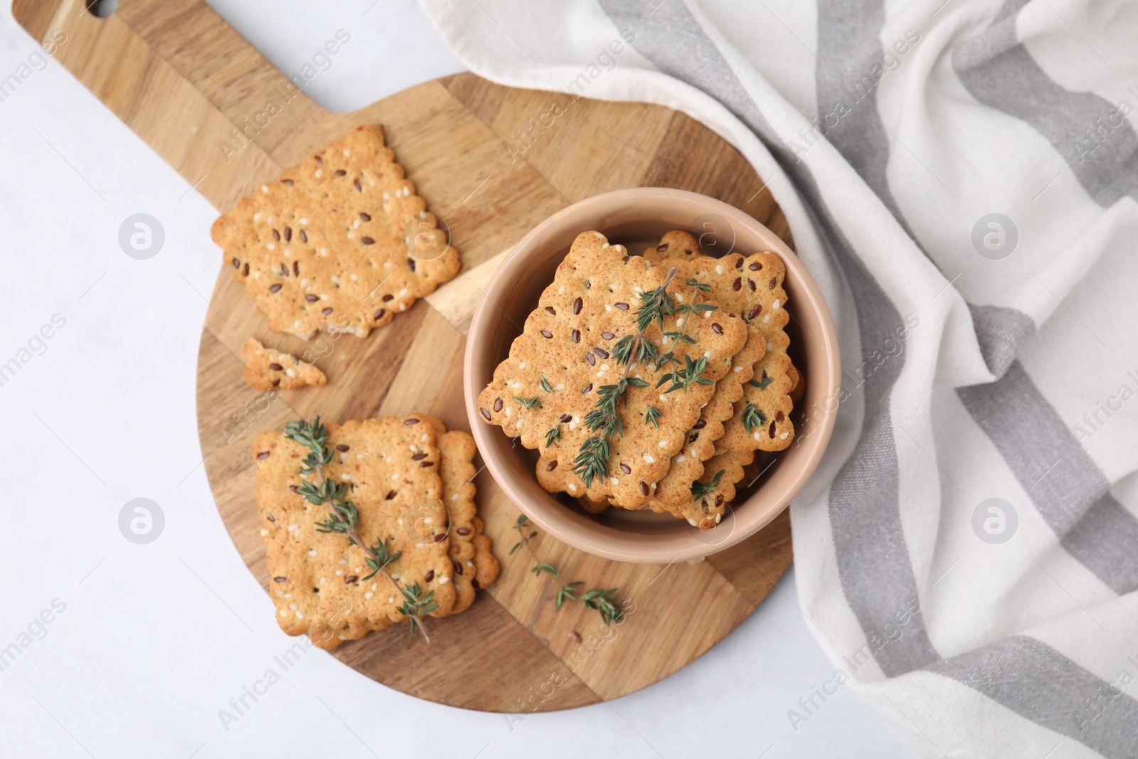 Photo of Cereal crackers with flax, sesame seeds and thyme in bowl on white table, top view