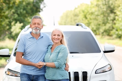 Photo of Happy senior couple posing near car outdoors