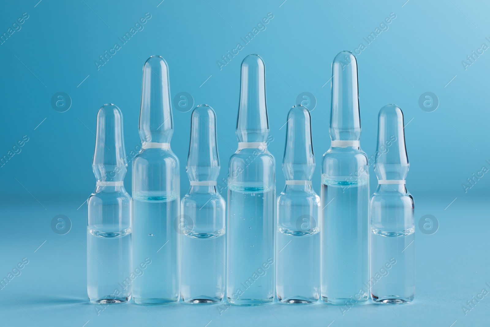 Photo of Many medical ampoules with solution for injection on light blue background
