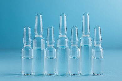 Photo of Many medical ampoules with solution for injection on light blue background