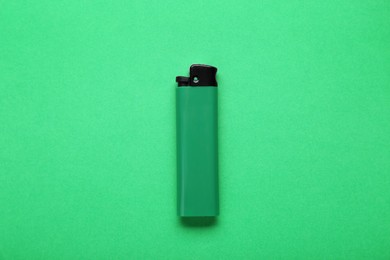 Photo of Stylish small pocket lighter on green background, top view