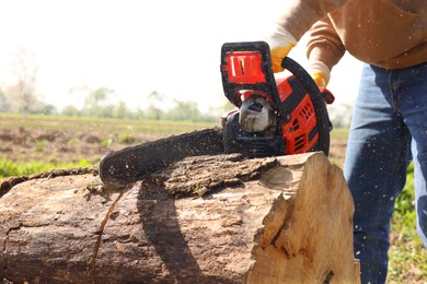 Photo of Man sawing wooden log on sunny day, closeup