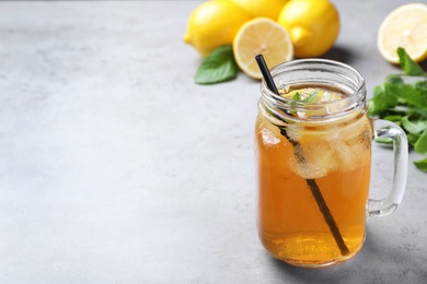 Photo of Delicious iced tea with lemon and mint on grey table. Space for text