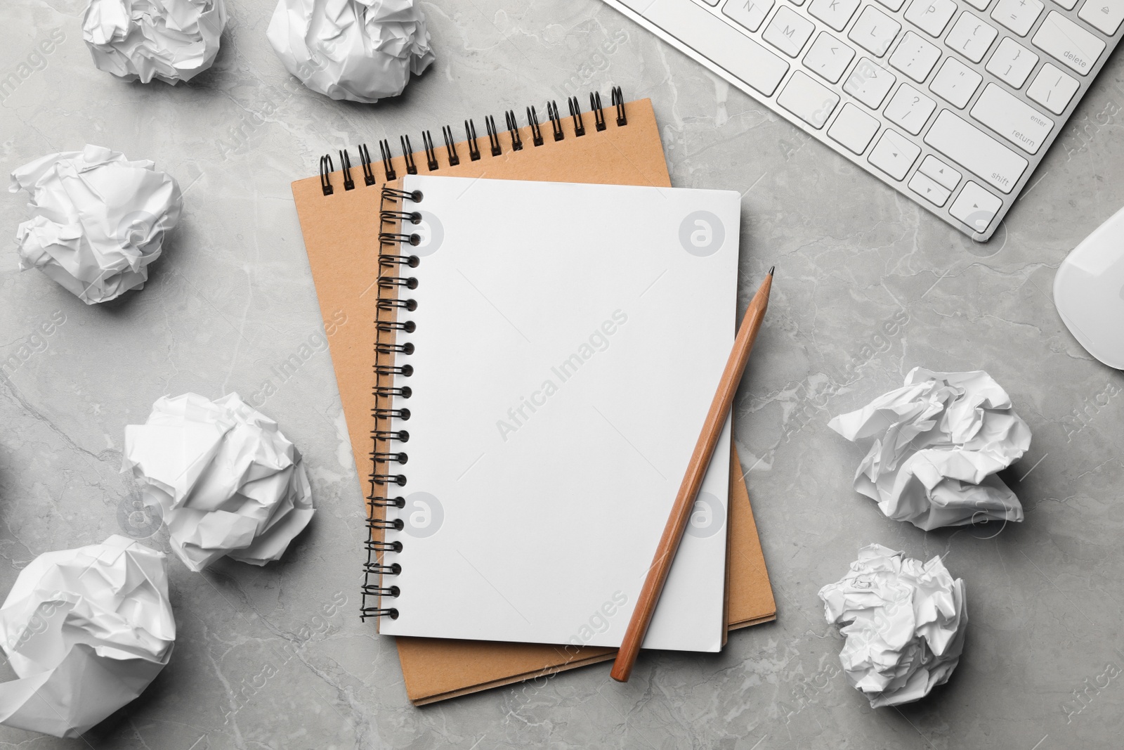 Photo of Flat lay composition with empty notebook and crumpled paper balls on grey marble table. Space for text