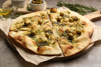 Delicious focaccia bread with green olives on marble table, closeup
