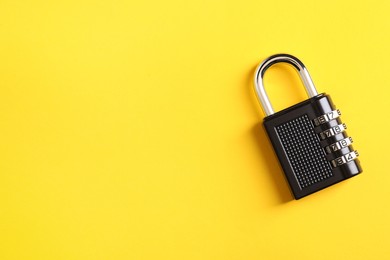 Photo of Steel combination padlock on yellow background, top view. Space for text