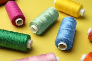 Photo of Different colorful sewing threads on yellow background