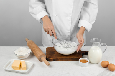 Photo of Woman whipping egg whites at wooden table, closeup. Baking pie