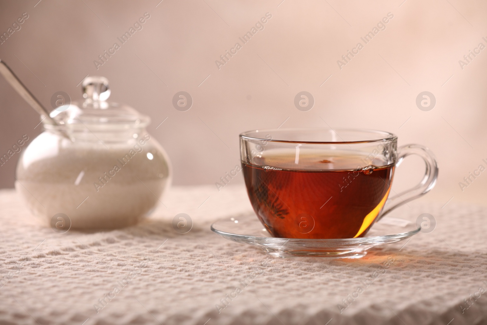 Photo of Aromatic tea in cup, saucer and sugar on table