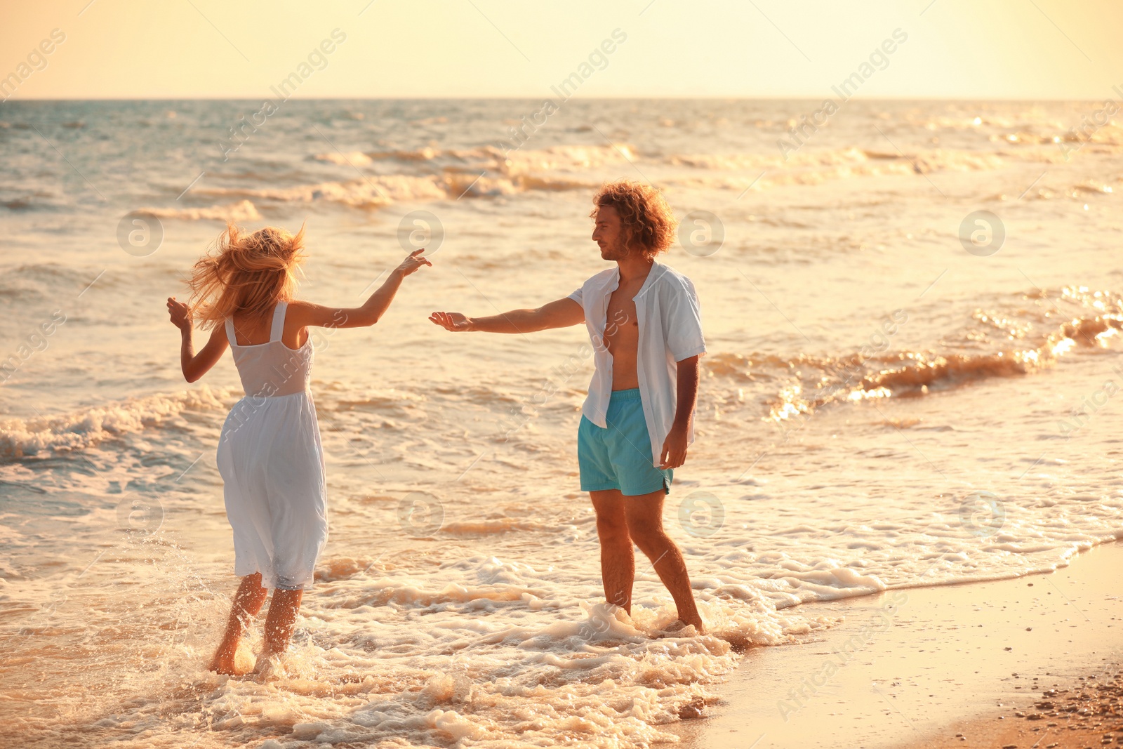 Photo of Young couple dancing on beach at sunset