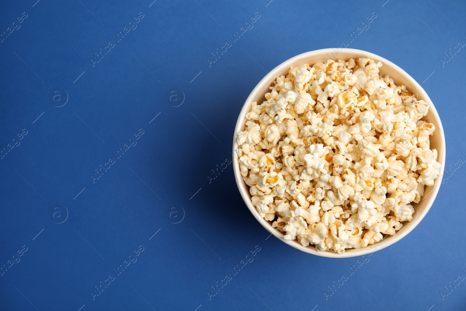 Photo of Tasty pop corn on blue background, top view. Space for text