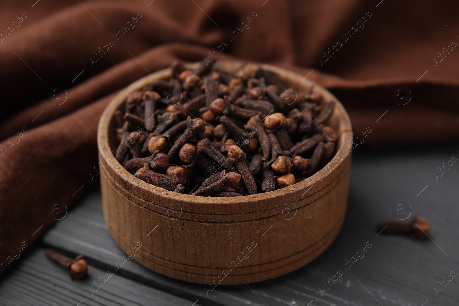 Photo of Aromatic cloves in bowl on grey wooden table, closeup