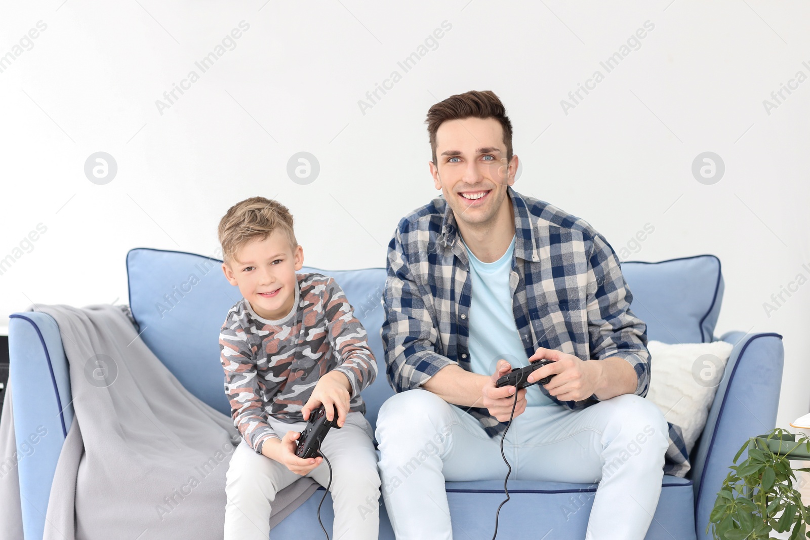 Photo of Happy dad and his son playing video games at home