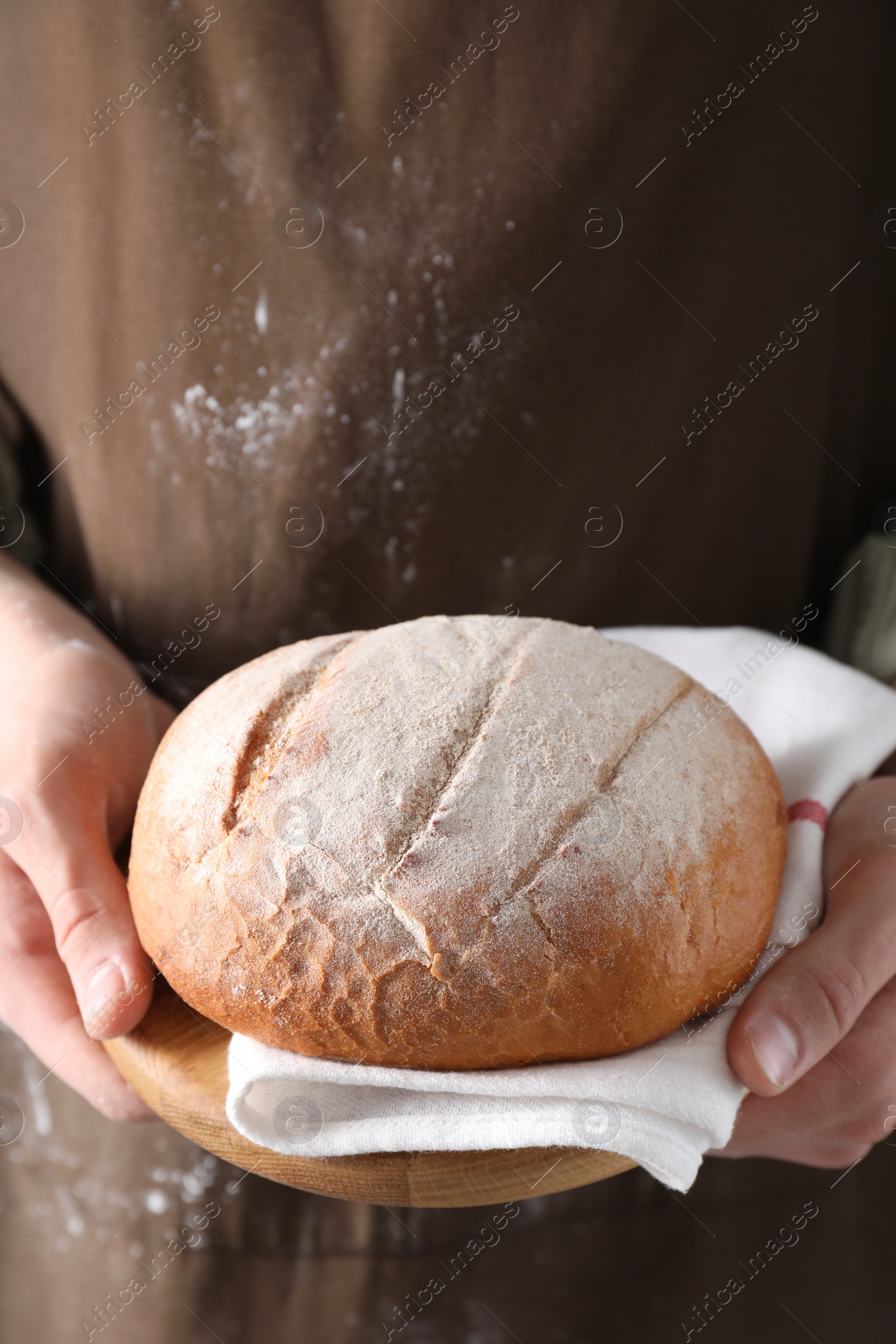 Photo of Woman holding one freshly baked bread, closeup