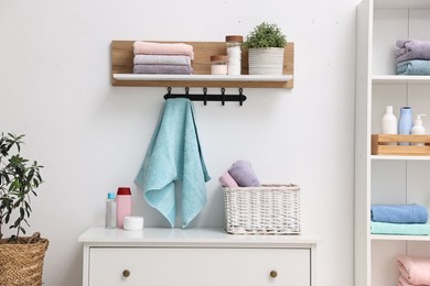 Shelving unit with stacked clean towels and toiletries in room