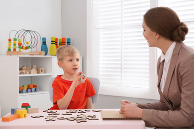 Photo of Speech therapist working with little boy in office