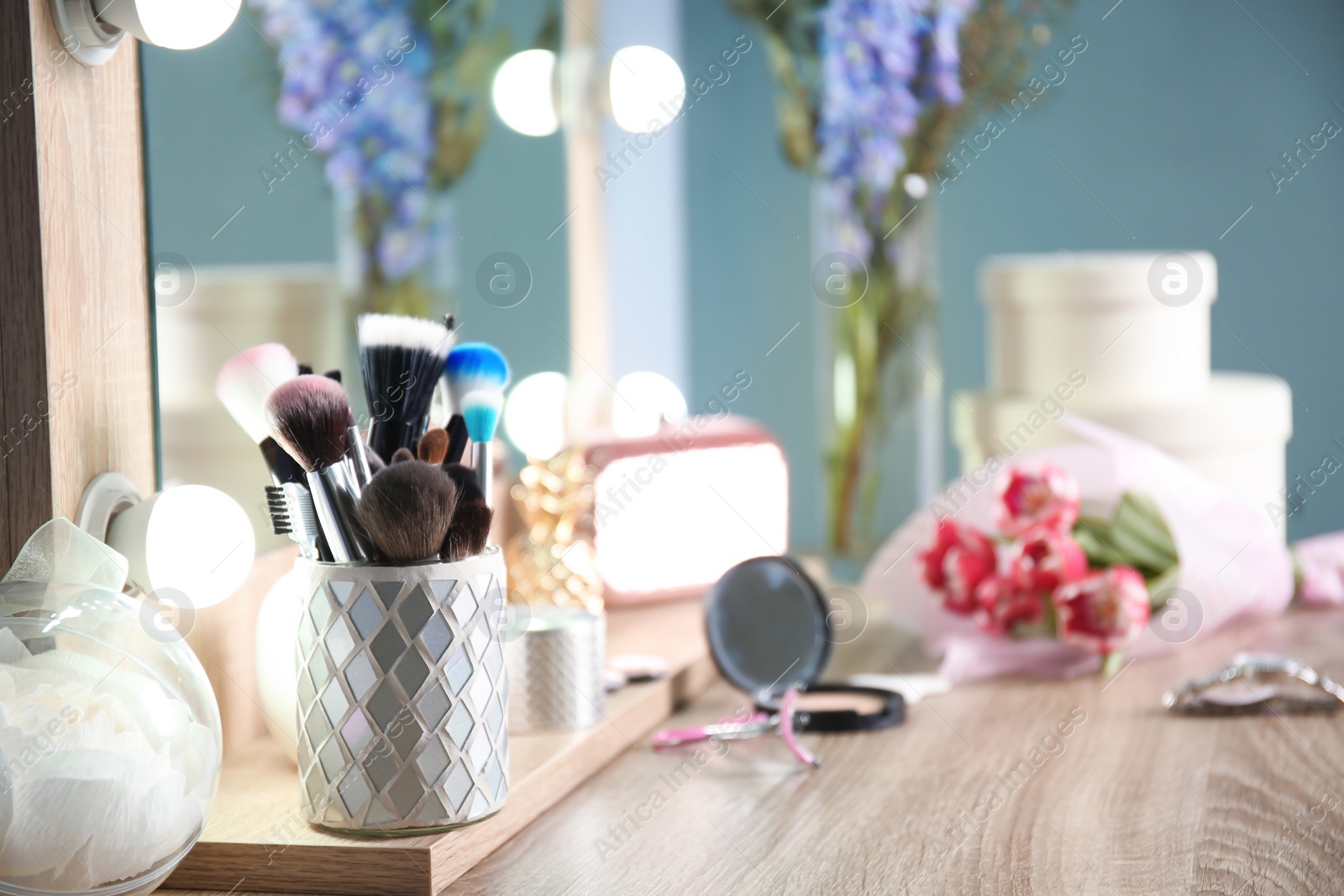 Photo of Holder with professional makeup brushes on wooden table