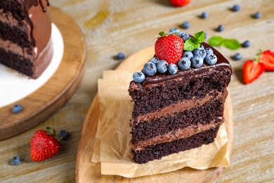 Piece of delicious chocolate cake decorated with fresh berries on wooden table