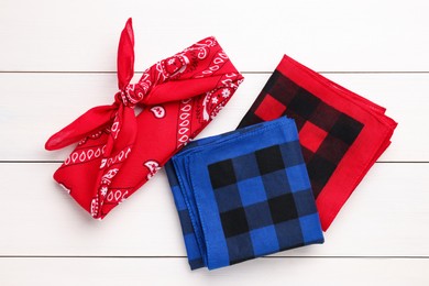 Photo of Stylish bandanas with different patterns on white wooden table, flat lay