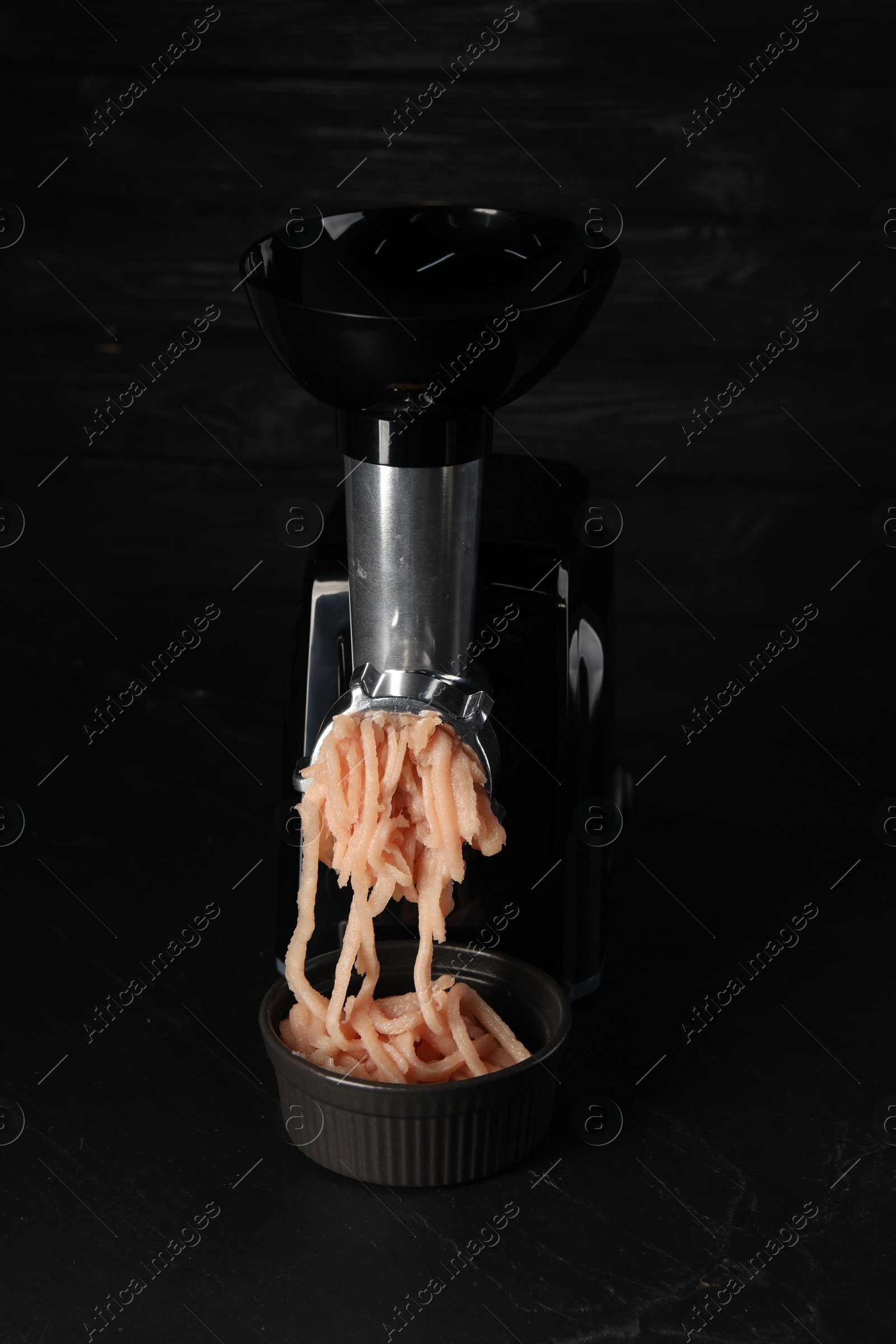 Photo of Electric meat grinder with chicken mince on black table