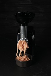Photo of Electric meat grinder with chicken mince on black table