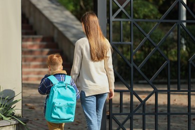 Photo of Young mom taking her son to school, back view