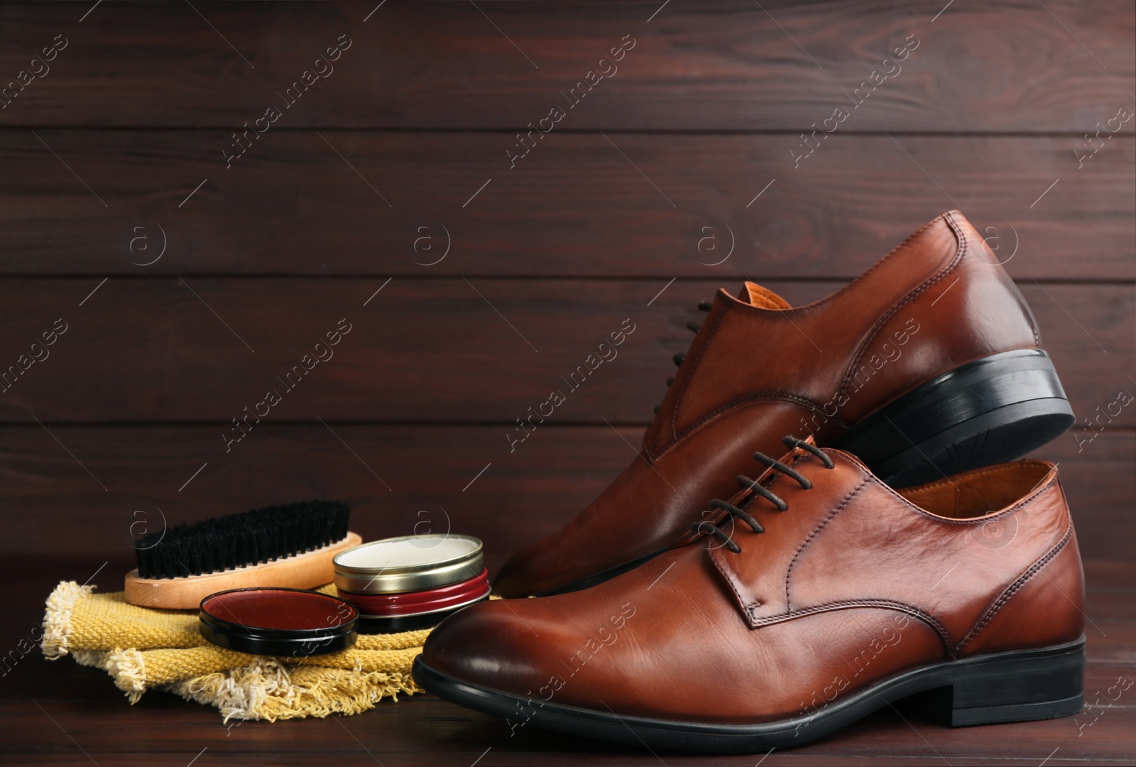 Photo of Shoe care products and footwear on wooden table. Space for text