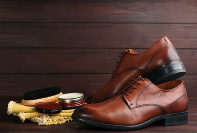 Photo of Shoe care products and footwear on wooden table. Space for text