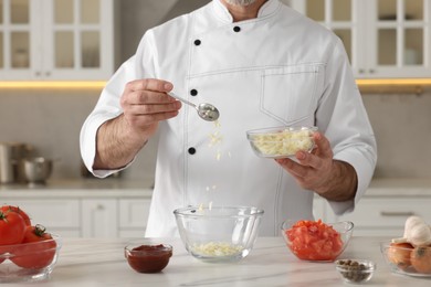 Photo of Professional chef making delicious tomato sauce at white marble table indoors, closeup
