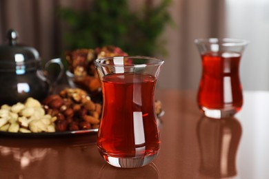 Photo of Glasses with tasty Turkish tea and sweets on brown table indoors