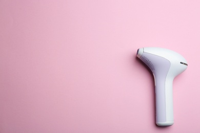 Photo of Modern photoepilator on pink background, top view. Space for text