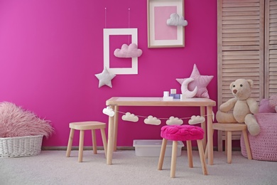 Photo of Modern interior of child game room with table, chairs and toys