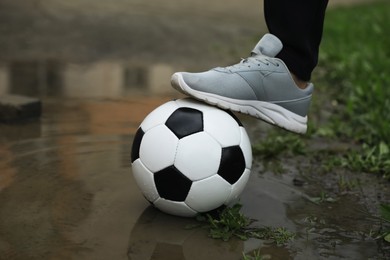 Photo of Man with soccer ball in puddle outdoors, closeup