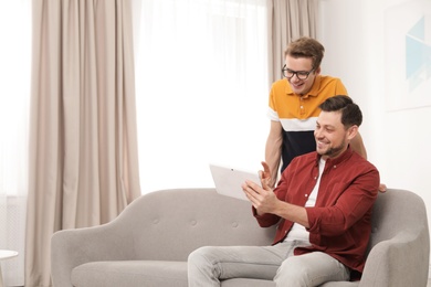 Happy father and his teenager son with tablet computer at home