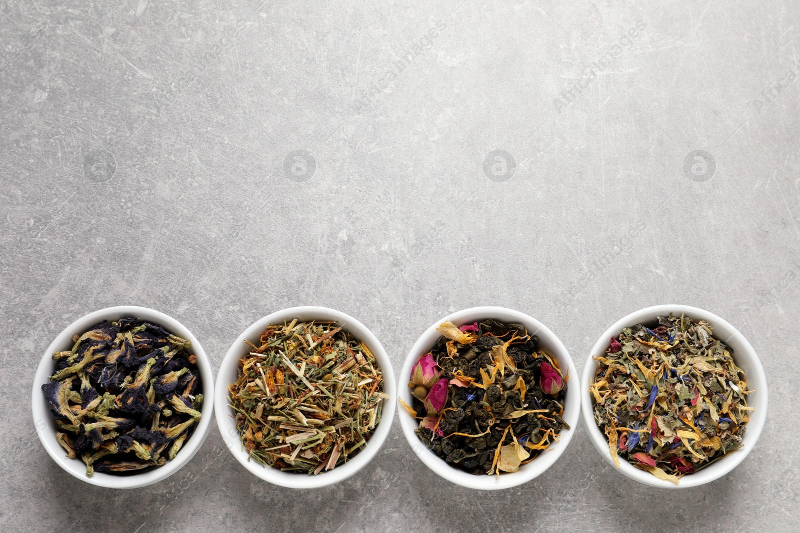 Photo of Flat lay composition with different dry teas on light grey table, space for text