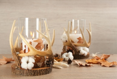 Photo of Burning candles in beautiful glass holders, cotton flowers and autumn leaves on wooden table