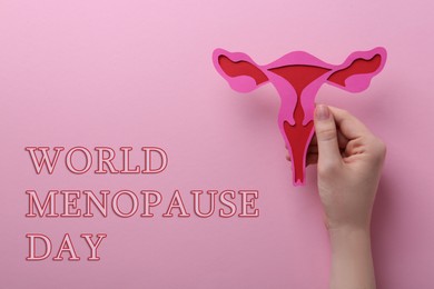 Image of World Menopause Day. Woman holding paper uterus on pink background, top view