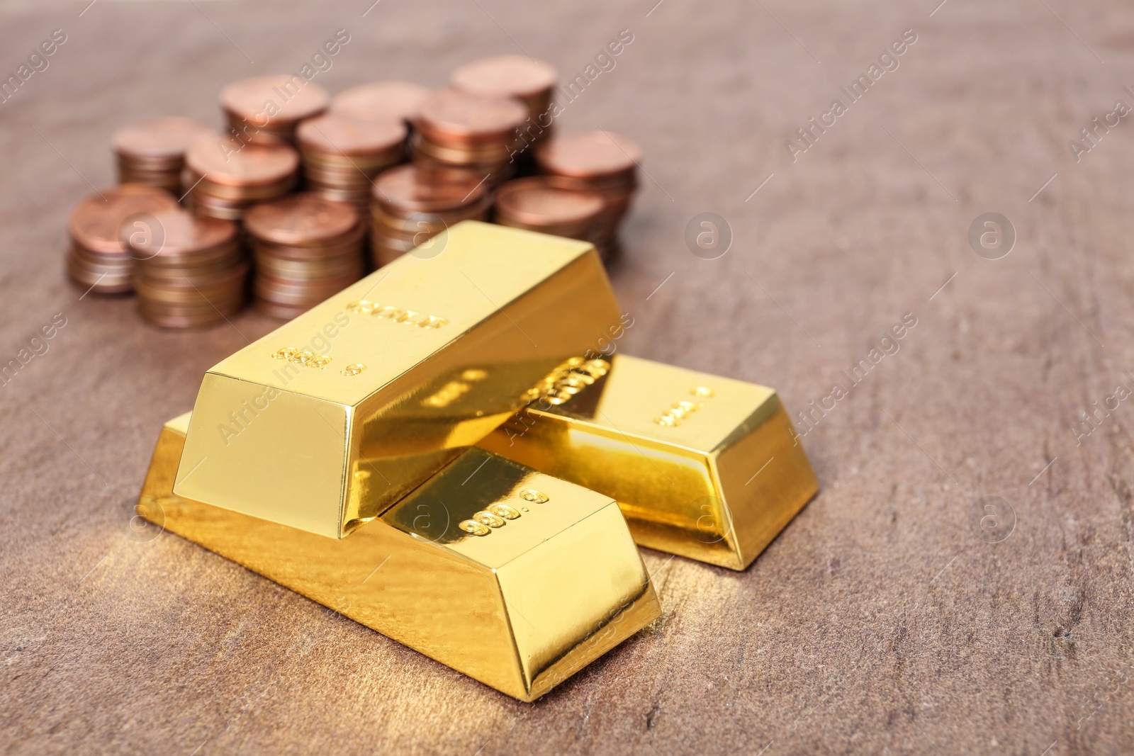 Photo of Stacked gold bars and coins on table. Space for text