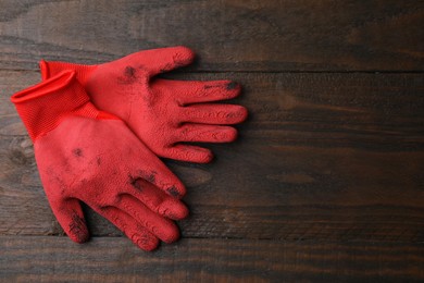 Pair of red gardening gloves on wooden table, top view. Space for text