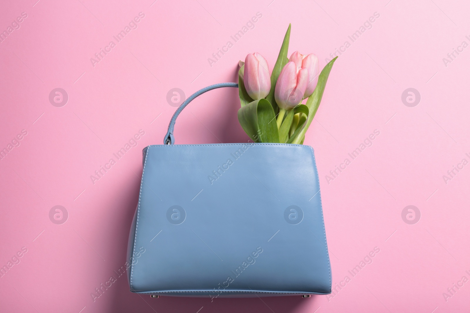 Photo of Flat lay composition with stylish woman's handbag and spring flowers on color background