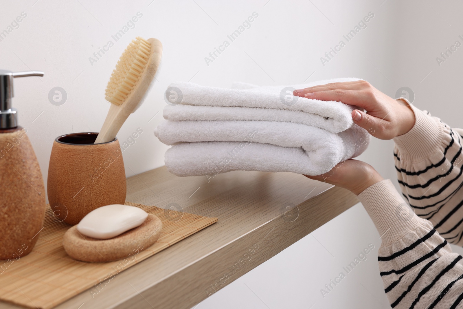 Photo of Bath accessories. Woman with stack of clean towels indoors, closeup