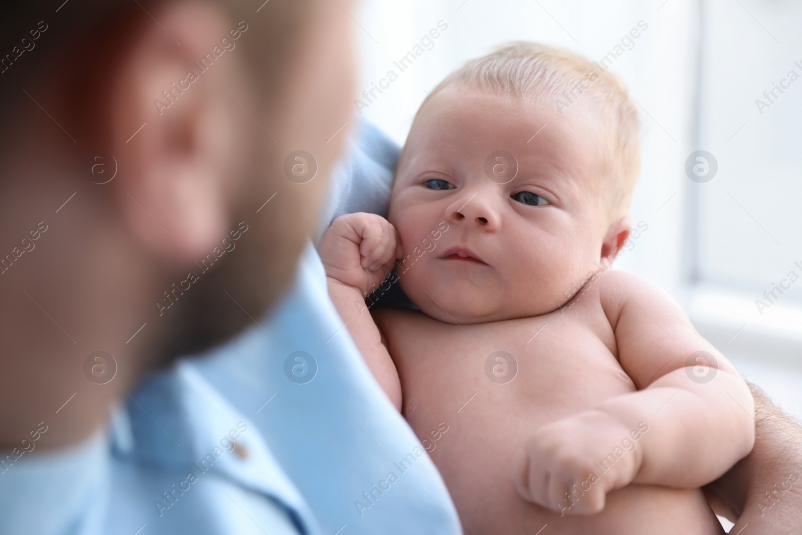 Photo of Father holding his cute newborn baby at home, closeup